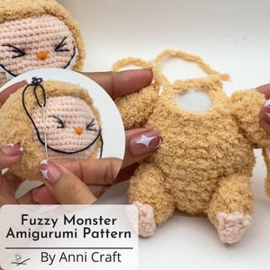 May include: A close-up of a fuzzy, light brown amigurumi monster being sewn. The monster has a light pink face with black stitched eyes and an orange beak. The text "Fuzzy Monster Amigurumi Pattern By Anni Craft" is at the bottom.