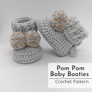 May include: A pair of grey crocheted baby booties with fluffy pom poms in grey and gold. Pom Pom Baby Booties Crochet Pattern.