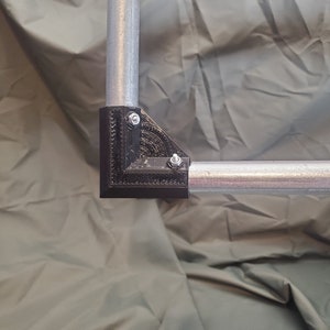 Puede incluir: Conector de esquina de plástico negro con dos tornillos para unir dos tuberías metálicas.