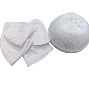 Puede incluir: Un conjunto de cinco gorros blancos de punto, también conocidos como gorros de oración, con un solo gorro blanco más grande en el fondo.