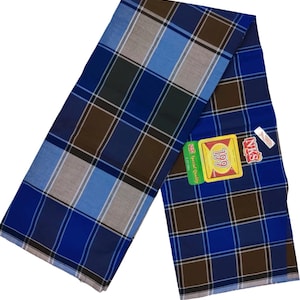 以下が含まれることがあります： 青、茶色、グレーのチェック柄サロン。生地は折りたたまれ、斜めに表示されています。199の数字が入ったタグが見えます。サロンは軽量素材でできており、暖かい気候に適しています。