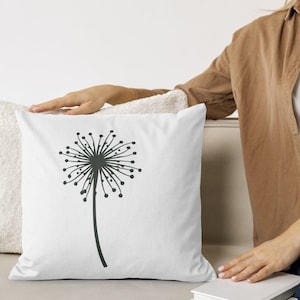 May include: White throw pillow with a black silhouette of a dandelion on it.