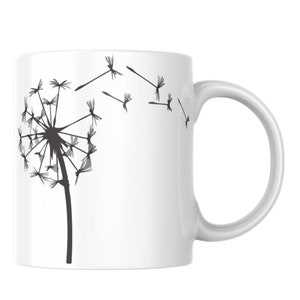 May include: White ceramic mug featuring a black and grey silhouette of a dandelion with seeds blowing in the wind.