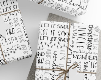 May include: Several wrapped gifts with white paper featuring black text and festive designs. The gifts are tied with twine and have blank tags. The text includes phrases like "Let it Snow" and "Jingle Christmas."