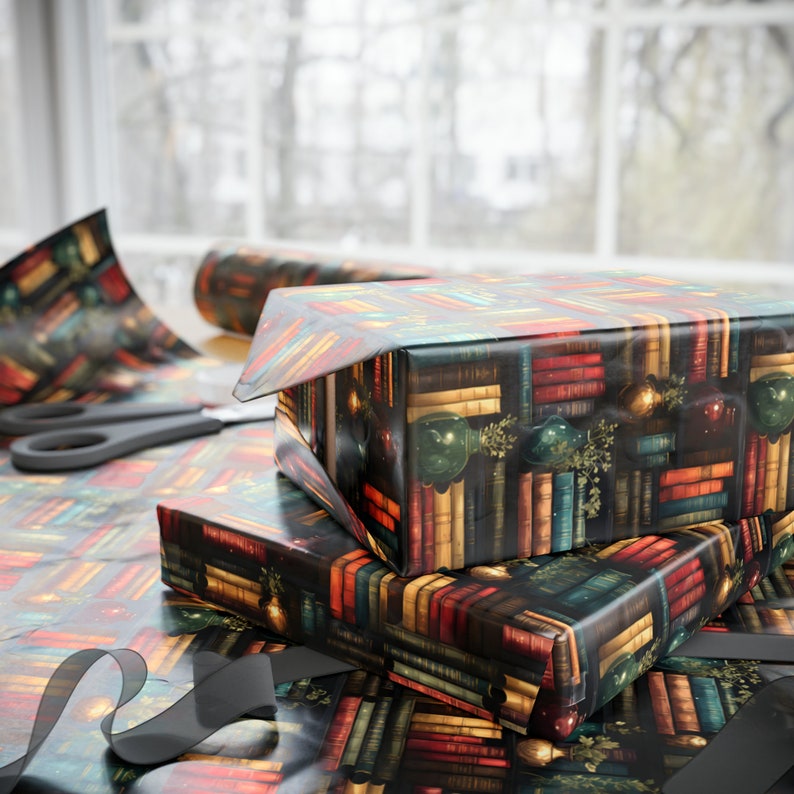 May include: A stack of three gift boxes wrapped in colorful patterned paper with a book theme. The boxes are wrapped in a dark background with colorful books and gold accents. The boxes are stacked on top of each other and are ready to be given as gifts.