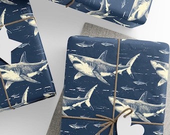 May include: Blue wrapping paper with a white shark pattern. The paper is wrapped around a gift box and tied with twine. A white heart-shaped tag is attached to the twine.