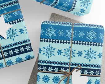 May include: Three wrapped gifts with blue snowflake patterned paper. The gifts are tied with twine and have white heart-shaped tags. The paper has a light blue background with darker blue snowflake and geometric designs.