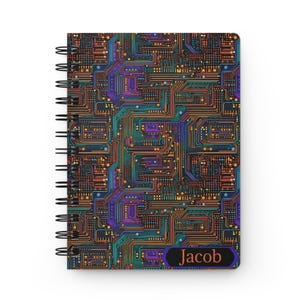 May include: A spiral-bound notebook featuring a colorful circuit board design in shades of orange, teal, purple, and gold. The notebook has a black spiral binding and the name "Jacob" printed on a black and purple label.
