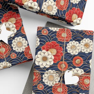 May include: Gift wrap featuring a repeating pattern of white and red flowers on a dark blue background. The flowers have gold accents and are surrounded by a wave-like pattern. The paper is tied with twine and a white heart-shaped tag.