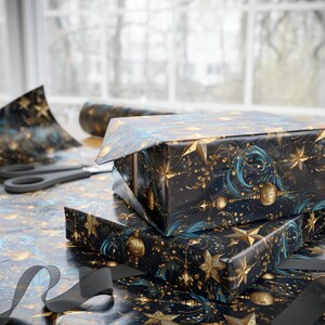 May include: Two gift boxes wrapped in black and gold patterned paper with blue accents. The boxes are stacked on top of each other and have a festive, holiday feel.