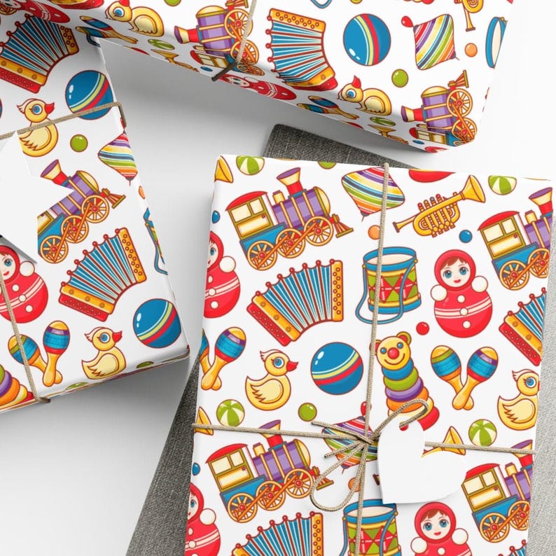 May include: White wrapping paper with a colorful pattern of toy-themed illustrations. The pattern includes a train, an accordion, a nesting doll, a toy drum, a rattle, a toy duck, and a ball.