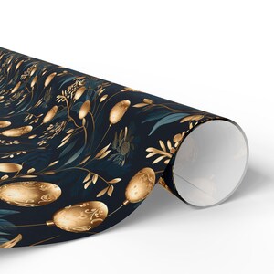 May include: A roll of wrapping paper with a dark blue background and a repeating pattern of gold-colored botanical illustrations. The design includes stylized leaves, seed pods, and floral elements.