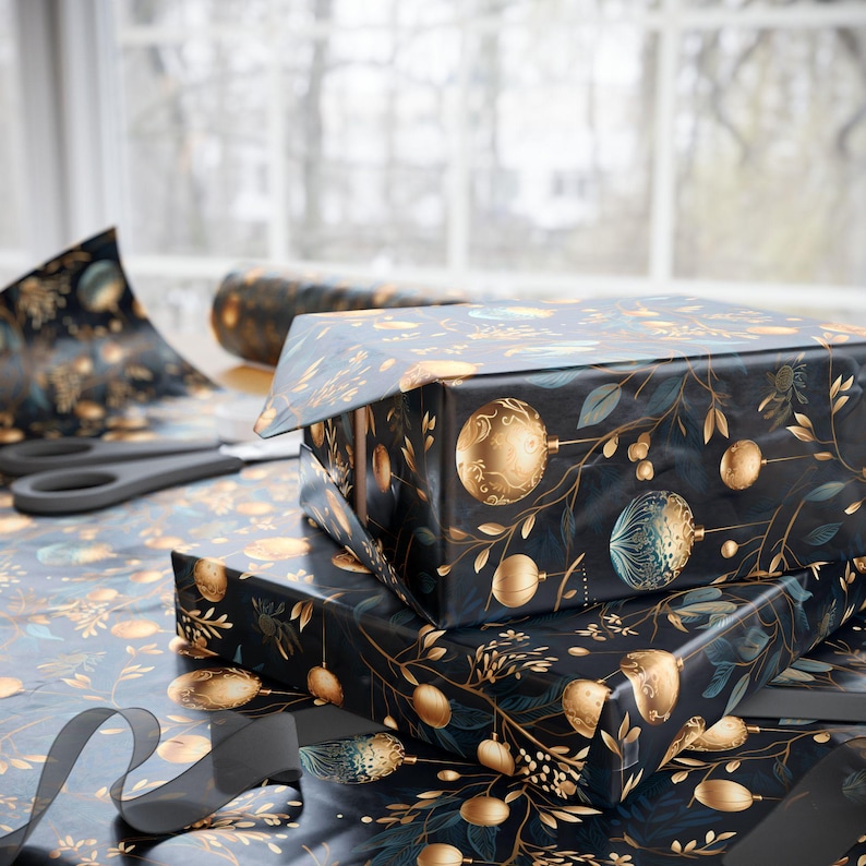 May include: Wrapped gift boxes with a festive design. The wrapping paper is dark blue with gold and teal ornaments and foliage. A roll of matching paper, scissors, and a ribbon are also visible.