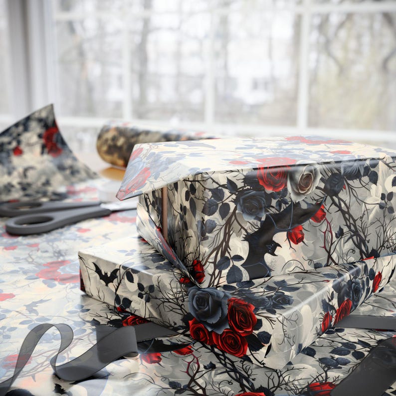 May include: Two gift boxes wrapped in black and white patterned wrapping paper with red and blue roses and a bat design. The wrapping paper has a vintage gothic aesthetic.