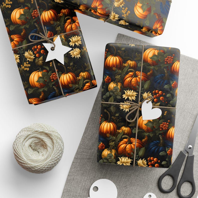 Op de afbeelding: Twee cadeaudozen ingepakt in donkerbruin papier met een patroon van oranje pompoenen, groene bladeren en witte bloemen. De dozen zijn vastgebonden met touw en versierd met witte papieren sterren en harten.