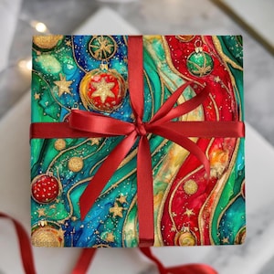 May include: A square gift box wrapped in colorful Christmas-themed paper. The paper features a vibrant design with ornaments, stars, and gold accents. A red ribbon is tied around the box in a bow.