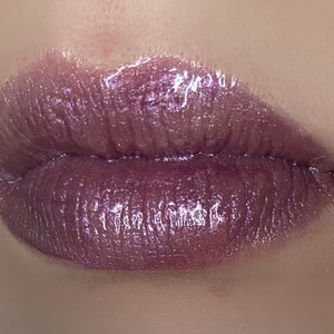 Peut inclure: Gros plan sur des lèvres portant un gloss à lèvres violet irisé et scintillant.