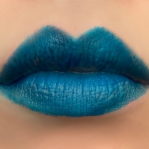 Könnte beinhalten: Nahaufnahme von Lippen, die einen leuchtend blauen Lippenstift tragen. Der Lippenstift hat ein mattes Finish und ist gleichmäßig aufgetragen.