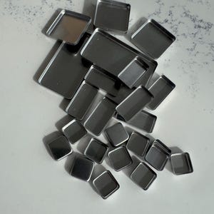 May include: A collection of silver metal square-shaped containers, some larger than others, are scattered on a white surface.