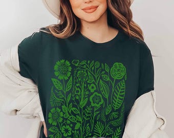 May include: A dark green short-sleeved t-shirt featuring a vibrant lime green graphic print of various stylized flowers, leaves, and botanical elements covering the center of the chest. The shirt has a crew neckline and a standard fit.