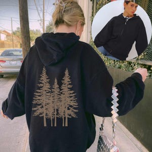 May include: Black hooded sweatshirt with a graphic of four brown trees on the back. The sweatshirt has a zipper and a drawstring hood.