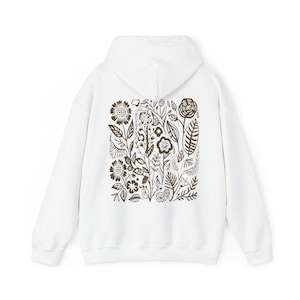 K&ouml;nnte beinhalten: Wei&szlig;er Kapuzenpullover mit braunem Blumendruck auf der R&uuml;ckseite.