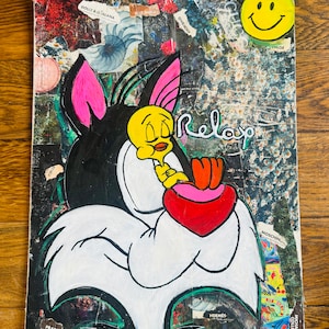 May include: A black and white cartoon cat with pink ears holding a red heart with the word "Relax" written in white. The background is a collage of colorful magazine clippings and a yellow smiley face.