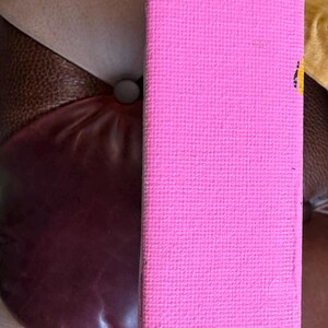 May include: A close-up of a pink canvas painting with a textured surface. The canvas is stretched over a wooden frame.