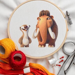 Peut inclure: Un cercle à broder avec une image de dessin animé d'un mammouth et d'un paresseux. L'image est entourée de fils à broder orange, jaune et rouge, d'un dé à coudre, d'aiguilles et de ciseaux. Le cercle est en bois.