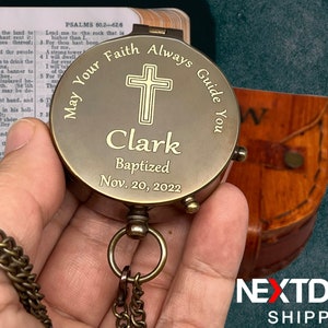 May include: A brass compass with a cross and the inscription "May Your Faith Always Guide You" and "Clark Baptized Nov. 20, 2022".