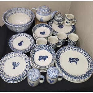 May include: A collection of white ceramic tableware with a blue floral pattern and animal motifs. The set includes bowls, plates, mugs, a teapot, and a sugar bowl. The animal designs include a rooster, cow, and pear.