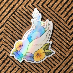 Puede incluir: Una pegatina holográfica con dos manos sosteniendo una llama azul con flores amarillas y hojas verdes. La pegatina tiene el texto "Tillman Project".