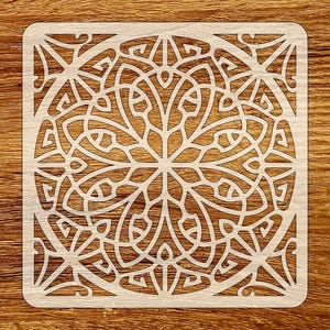 Może przedstawiać: Kwadratowy szablon z szczegółowym, symetrycznym wzorem. Szablon ma powtarzający się wzór połączonych kształtów i linii, tworząc złożony, ażurowy wzór. Szablon jest jasny, prawdopodobnie drewniany i umieszczony na drewnianym tle.