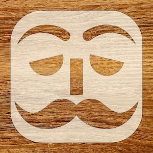 May include: A stencil featuring a stylized face with arched eyebrows, downturned eyes, a rectangular nose, and a large mustache. The stencil is cut from a light-colored material and set against a wood grain background.