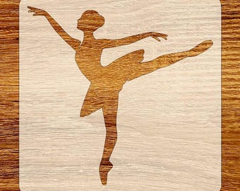 May include: A wooden stencil featuring a ballerina in a graceful pose. The ballerina is depicted with one leg extended and arms outstretched. The stencil is square with rounded corners and is made of light-colored wood.