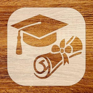 May include: A graduation-themed stencil featuring a mortarboard cap and a rolled diploma tied with a bow. The design is cut out of a square shape with rounded corners, revealing the wood grain background. The cap has a tassel, and the diploma is tied with a bow.