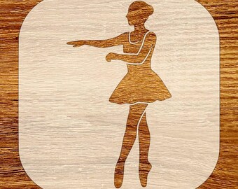 May include: Wooden stencil featuring a ballerina in a graceful pose. The dancer is depicted in a flowing dress and ballet shoes, with one arm extended. The stencil is set against a light background with a rounded square shape.