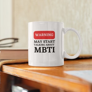 May include: White ceramic mug with a red warning sign that says "WARNING MAY START TALKING ABOUT MBTI".