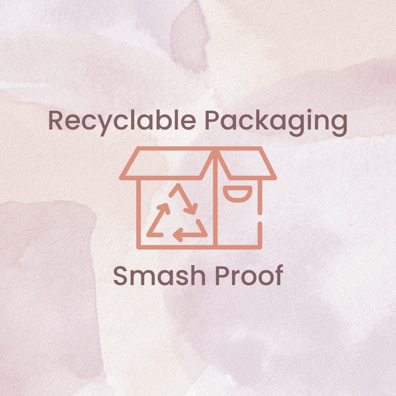 May include: A brown line drawing of a box with a recycle symbol inside. The text "Recyclable Packaging" is above the box and the text "Smash Proof" is below the box. The background is a watercolor wash of pink and white.