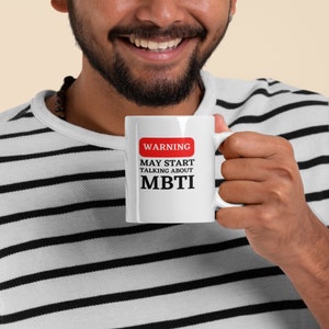 May include: White ceramic mug with a red warning sign that says "WARNING MAY START TALKING ABOUT MBTI".