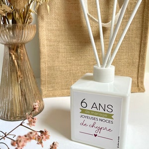 May include: White diffuser bottle with a label that says "6 ANS de mariage JOYEUES NOCES de chypre". The bottle has white sticks sticking out of the top.