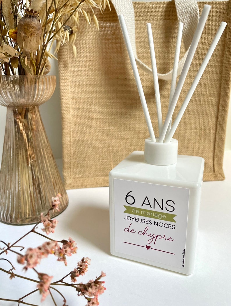 May include: White diffuser bottle with a label that says "6 ANS de mariage JOYEUES NOCES de chypre". The bottle has white sticks sticking out of the top.