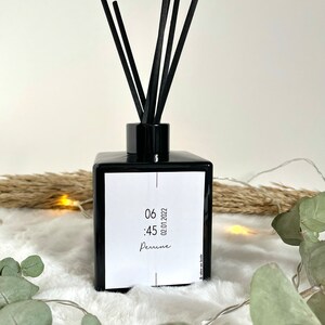 May include: Black diffuser bottle with black reeds and a white label with the text "06:45 02.01.2022 Perrine".