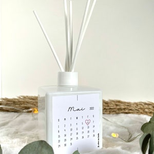 May include: White diffuser bottle with a calendar sticker featuring the month of May 2022. The number 6 is highlighted with a red heart.