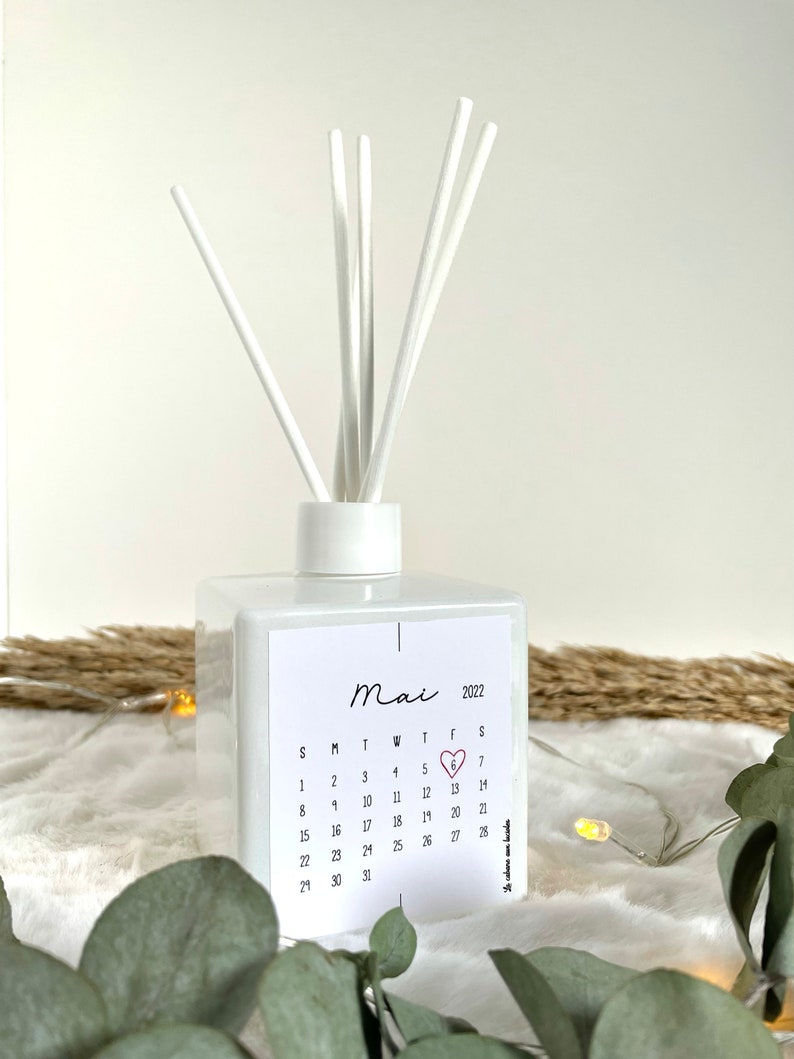 May include: White diffuser bottle with a calendar sticker featuring the month of May 2022. The number 6 is highlighted with a red heart.