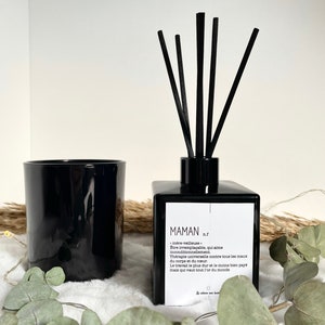 May include: Black glass diffuser bottle with black reeds and a white label that reads "MAMAN n.f.  m&egrave;re-veillleuse &Ecirc;tre irrempla&ccedil;able, qui aime inconditionnellement. Th&eacute;rapie universelle contre tous les maux du corps et du c&oelig;ur Le travail le plus dur et le moins bien pay&eacute; mais qui vaut tout l'or du monde"