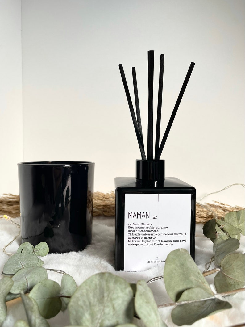 May include: Black glass diffuser bottle with black reeds and a white label that reads "MAMAN n.f.  m&egrave;re-veillleuse &Ecirc;tre irrempla&ccedil;able, qui aime inconditionnellement. Th&eacute;rapie universelle contre tous les maux du corps et du c&oelig;ur Le travail le plus dur et le moins bien pay&eacute; mais qui vaut tout l'or du monde"