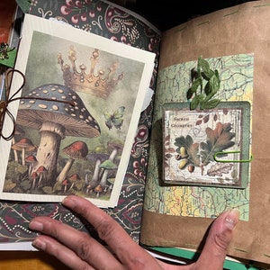 May include: A scrapbook page with a green and brown patterned paper background. The page features a vintage illustration of mushrooms with a crown on top, and a smaller card with the text "Sacred Geometry".