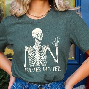 May include: A green t-shirt with a white skeleton graphic giving a thumbs up and the text "NEVER BETTER".