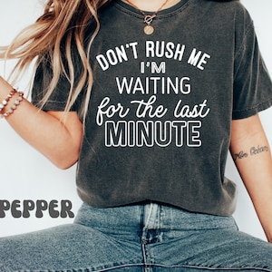 May include: A dark gray t-shirt with the text "Don't rush me I'm waiting for the last minute" in white lettering.